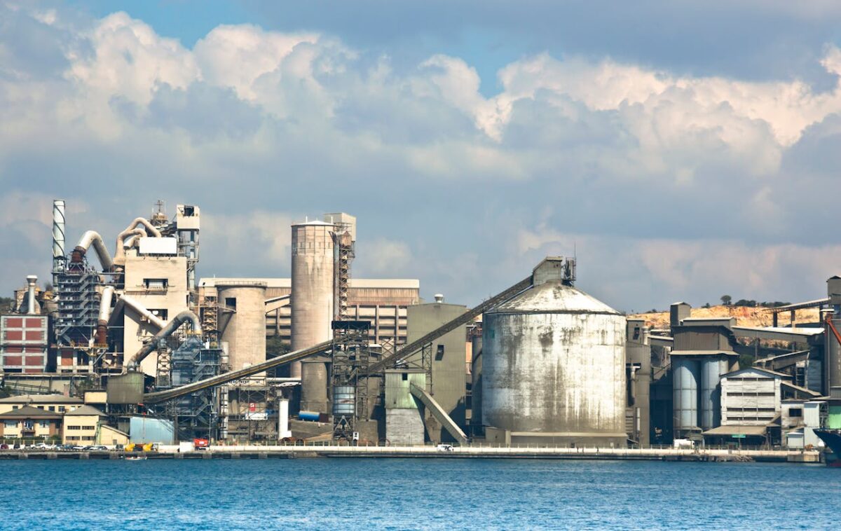 A sprawling industrial factory complex by the sea, captured on an overcast day, showcasing diverse structures.