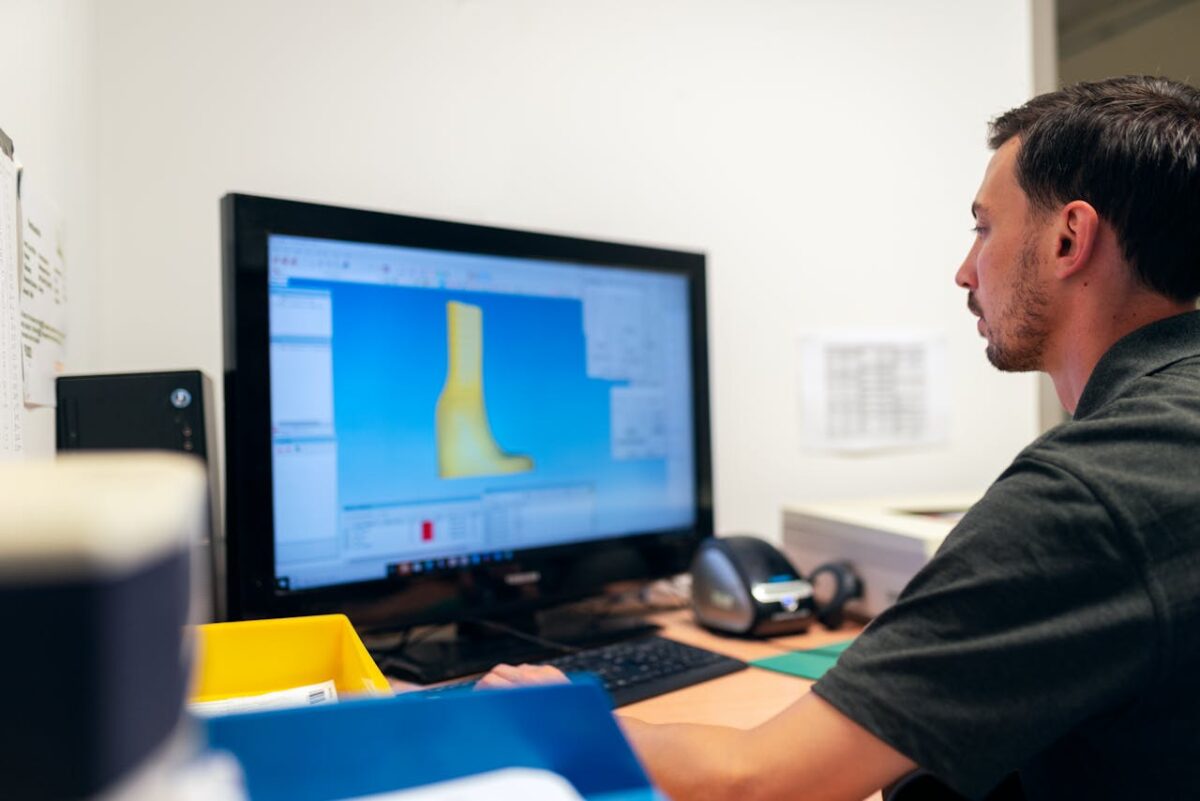 Engineer working on prosthetic design using specialized software in an office setting.