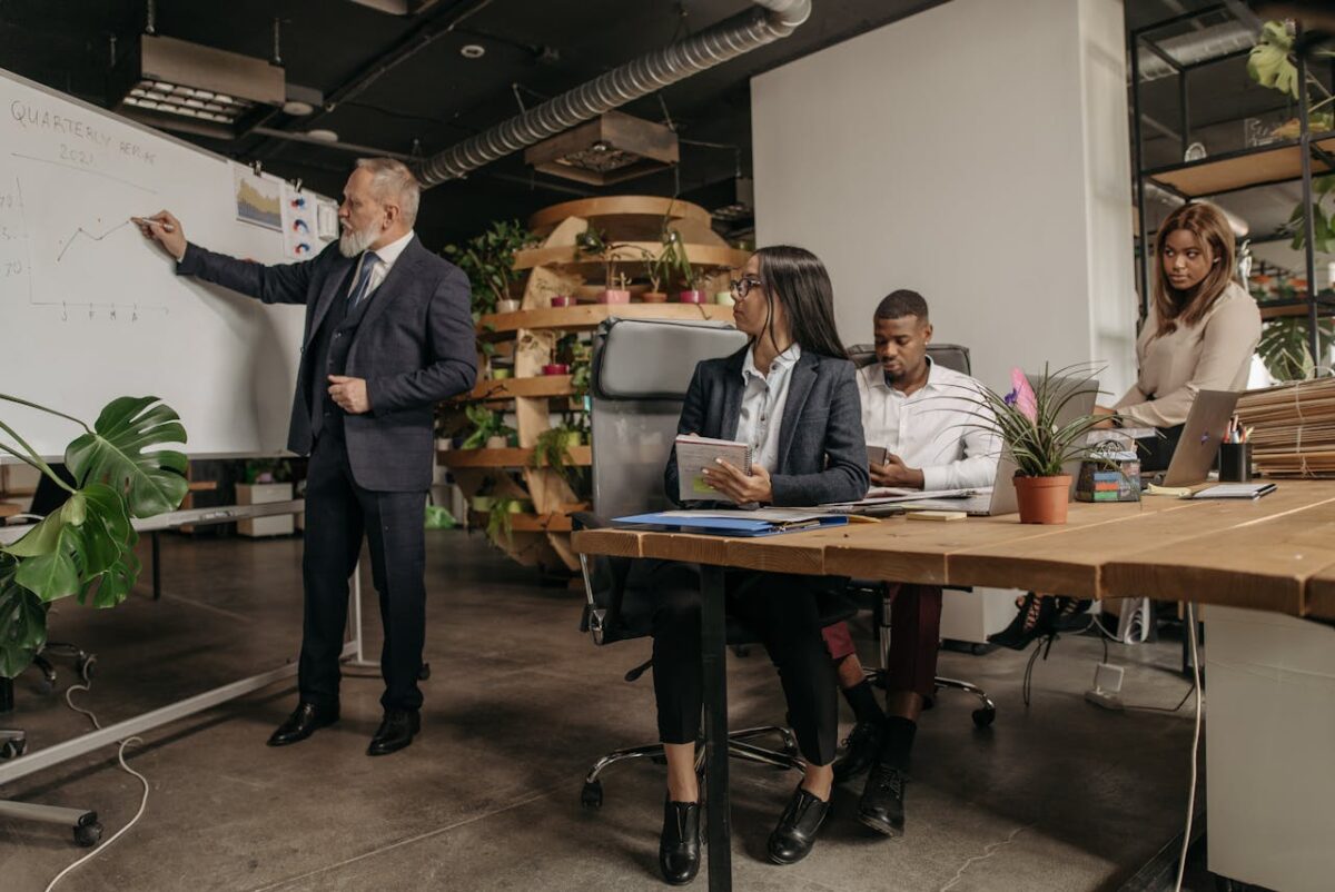 Business professionals engage in a team meeting with a whiteboard presentation in a modern office.